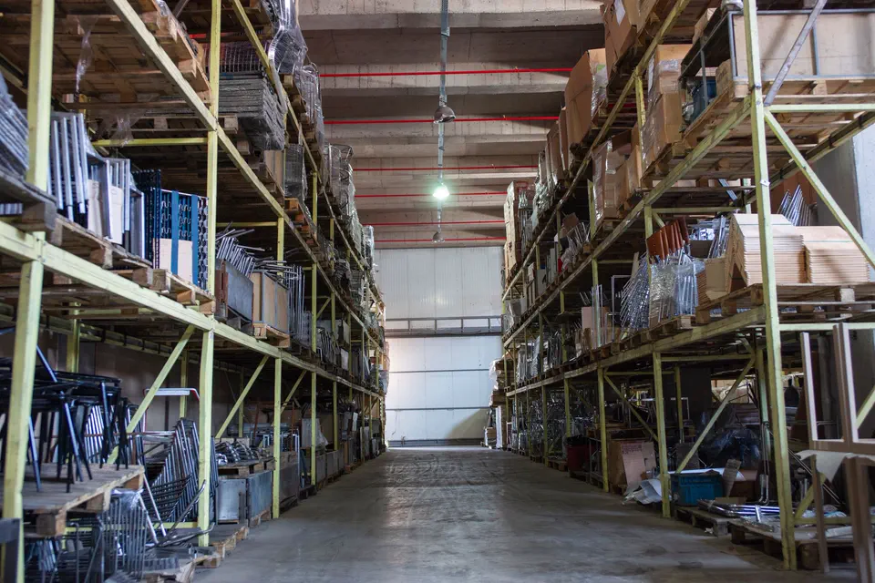 Allée d'entrepôt logistique avec rayonnages et palettes stockées.